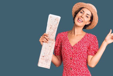 Yazlık şapka takan genç ve güzel bir kadın. Gülümsüyor, mutlu bir şekilde elini ve parmağını yana doğru gösteriyor. 