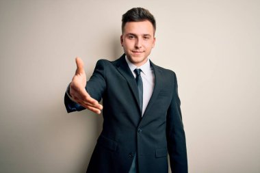 Zarif takım elbiseli ve kravatlı genç yakışıklı iş adamı mutlu bir şekilde gülümseyerek yardım eli uzatıyor ve kabul ediyor..