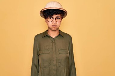 Genç ve güzel Afro-Amerikan turist kadın gözlüklü ve kaşif şapkalı komik yüzlü yanakları şişiren. Havayla şişmiş ağız, çılgın bir ifade..
