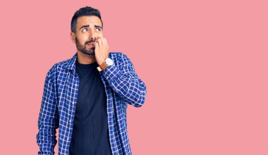 Günlük kıyafetler giyen genç İspanyol adam gergin ve gergin görünüyor. Ağzı tırnak yiyen eller. anksiyete. 