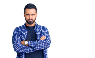 Gündelik kıyafetler giyen, kuşkucu ve gergin genç İspanyol bir adam. Yüzünde çapraz kollarla onaylamayan bir ifade var. negatif kişi. 