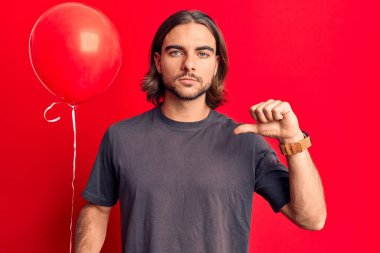 Kızgın yüzlü, genç ve yakışıklı bir adam. Negatif işaretler, baş parmakları aşağıda, reddedilme kavramı. 