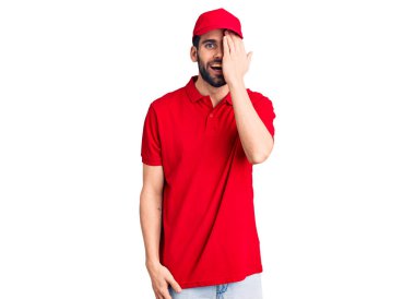 Sakallı yakışıklı adam teslimat üniforması giyiyor. Bir gözünü eliyle kapatıyor. Yüzünde kendine güvenen bir gülümseme ve sürpriz bir duygu var.. 