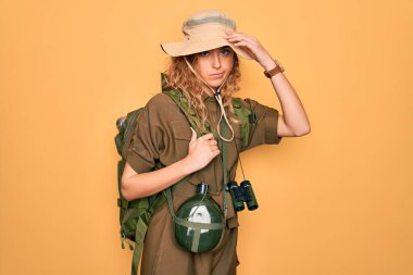 Mavi gözlü genç sarışın kaşif sırt çantası ve su matarası takıyor. Alnındaki sorun yüzünden endişeli ve stresli. Kriz için endişeli.