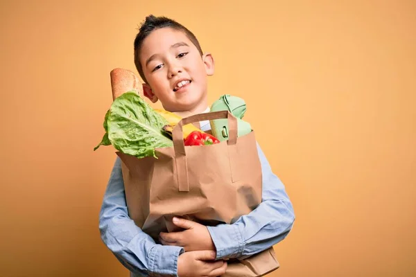 Entzückendes Kleinkind Hält Papiertüte Mit Essen Über Isoliertem Gelben Hintergrund — Stockfoto