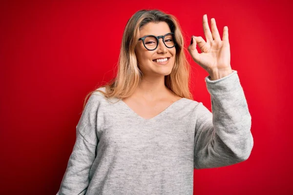 Giovane Bella Donna Bionda Indossa Maglione Occhiali Sfondo Rosso Isolato — Foto Stock