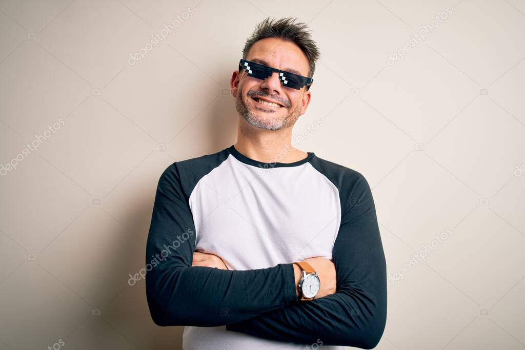 Young handsome man wearing funny thug life sunglasses meme over white background happy face smiling with crossed arms looking at the camera. Positive person.