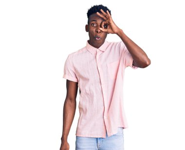 Genç Afro-Amerikan bir adam günlük giysiler giyiyor. Şaşırmış yüz ifadesiyle şaşırmış, parmaklarının arasından bakıyor. İnançsız ifade. 