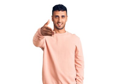 Gündelik kıyafetler giyen genç İspanyol adam dostça bir selamlama ve hoş geldin hediyesi olarak el sıkışmayı sunuyor. başarılı iş. 