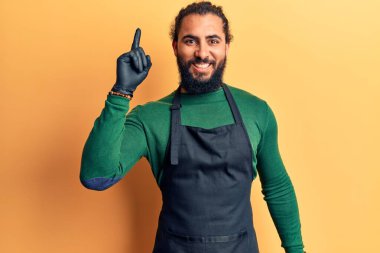 Berber önlüklü genç bir Arap başarılı bir fikir işaret ediyor. Heyecanlı ve mutlu. Bir numara.. 