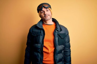 Genç kayakçı kayak yapıyor kar gözlüğü takıyor uykulu ve yorgun görünüyor, yorgunluktan ve akşamdan kalmalıktan yorgun ve tembel gözlü..