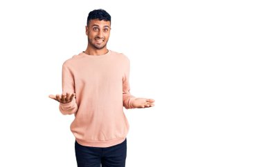 Gündelik kıyafetler giyen genç İspanyol adam güler yüzlü, kolları açık, dostça karşılama, olumlu ve kendinden emin selamlar. 