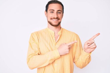 Gündelik kıyafetler giyen, gülümseyen ve kameraya bakan genç, yakışıklı bir adam.. 