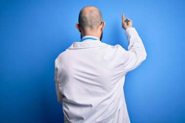 Sakallı, mavi arka planda steteskop takan yakışıklı, kel bir doktor.