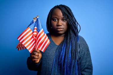 Genç, vatansever, Afro-Amerikan ve örgülü kadın. Birleşik Devletler bayrakları taşıyor. Zeki suratında kendine güvenen bir ifade var.