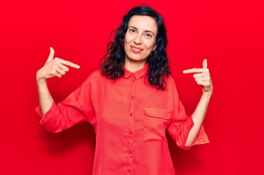 Genç ve güzel İspanyol kadın gündelik kıyafetler giyiyor. Kendine güveniyor gibi görünüyor. Yüzünde gülücüklerle kendini gururlu ve mutlu olarak gösteriyor.. 