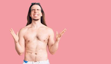 Uzun saçlı, mayosuz, çılgın ve başarının delicesine kutlama yapan genç bir adam. Kolları havada ve gözleri kapalı, heyecanlı bir şekilde bağırıyor. Kazanan konsept 