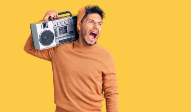Yakışıklı Latin Amerikalı genç adam elinde teyp ile öfkeli ve öfkeli çığlıklar atan, öfkeyle bağıran müzik dinliyor. öfke ve agresif konsept. 