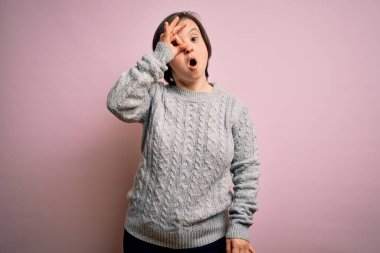 Down sendromlu genç bir kadın izole edilmiş arka planda sıradan bir süveter giyiyor. Şaşırmış yüz ve gözlerle parmaklarından bakıyor. İnançsız ifade.