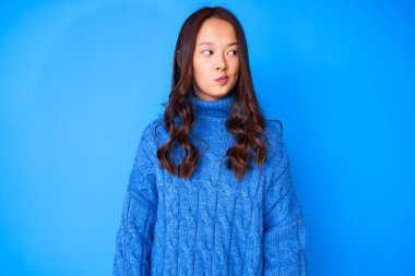 Genç, güzel, Çinli bir kız, sıradan bir kazak giyiyor. Gülümsüyor, yan tarafa bakıyor ve düşünüyor.. 