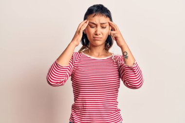 Elleri başının üstünde, günlük kıyafetler giyen genç bir kadın. Stres yüzünden baş ağrısı çekiyor. migren ağrısı. 