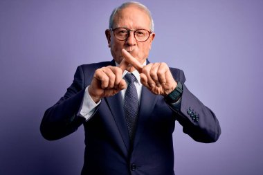 Gri saçlı, gözlüklü, şık takım elbiseli ve mor arka planda kravat takan kıdemli iş adamı. Reddedilme ifadesinin olumsuz işaret vermesi için dua ediyorum.