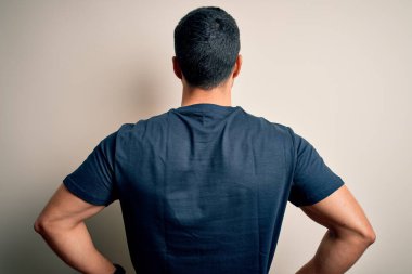 Sakallı, tişörtlü, beyaz arka planda gönüllü mesajı olan yakışıklı adam kolları vücudunda geriye doğru bakıyor.