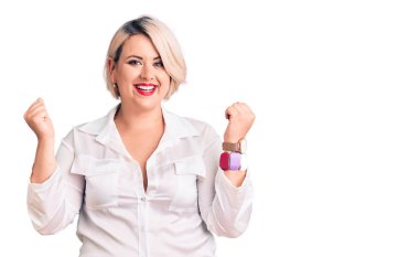 Sarışın, iri yarı, sıradan bir gömlek giyen genç bir kadın kolları açık ve gözleri açık bir şekilde başarıyı kutluyor ve şaşırıyor. Kazanan konsept. 