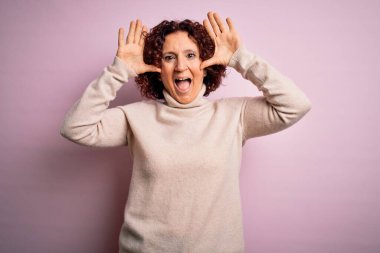 Orta yaşlı, kıvırcık saçlı, pembe arka planda balıkçı yaka kazak giyen neşeli gülümseyen, elleri havada dikizleme oyunu oynayan güzel bir kadın. Şaşırdım ve çıktım.