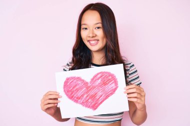 Elinde kalp şeklinde kağıt tutan genç, güzel Çinli bir kız. Pozitif ve mutlu görünüyor. Kendine güvenen bir gülümsemeyle, dişlerini gösteriyor. 