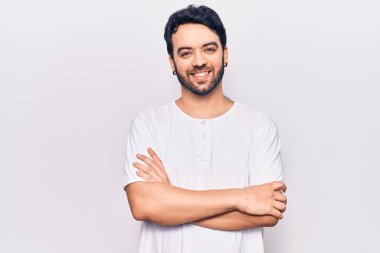 Gündelik kıyafetler giyen, kollarını kavuşturup kameraya gülümseyen genç İspanyol adam. pozitif kişi. 