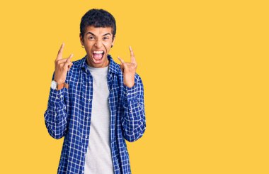 Genç Afrikalı Amerikalı sıradan kıyafetler giymiş çılgın bir ifadeyle bağırıyor elleri havada rock sembolü yapıyor. Müzik yıldızı. ağır müzik konsepti. 