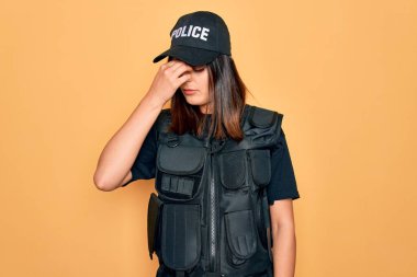 Genç, güzel, esmer, polis üniforması giyen, kurşun geçirmez giyen, şapkalı, burnu ve gözleri ovuşturmaktan yorgun düşmüş, yorgun ve başı ağrıyan bir kadın. Stres ve hüsran kavramı.