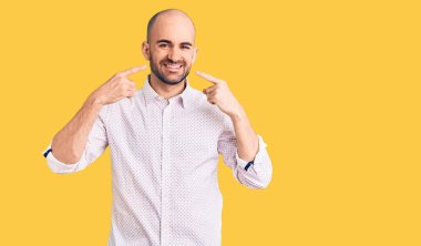 Zarif gömlekler giyen, neşeli gülümseyen, parmaklarını ve ağzını gösteren genç yakışıklı bir adam. diş sağlığı kavramı. 