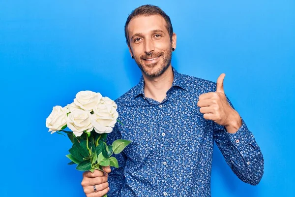 Jovem Homem Bonito Segurando Flores Sorrindo Feliz Positivo Polegar Para — Fotografia de Stock