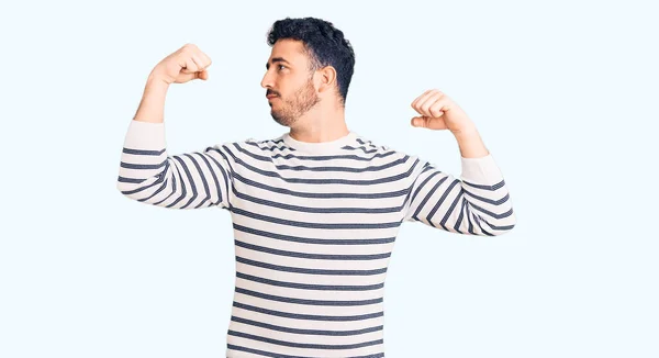 Jovem Hispânico Vestindo Roupas Casuais Mostrando Músculos Dos Braços Sorrindo — Fotografia de Stock