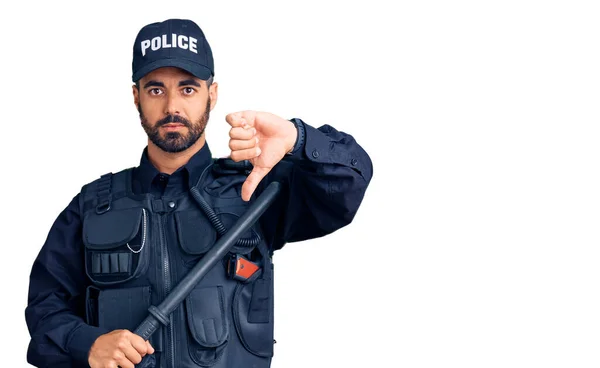 怒った顔をした警察の制服を着た若いヒスパニック系の男 親指を下げて嫌いであることを示す負の記号 拒絶概念 — ストック写真