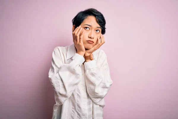 年轻美丽的亚洲女孩穿着休闲装 站在孤立的粉色背景之上 疲惫的手捂住脸 忧郁和悲伤 心烦意乱 焦躁不安 — 图库照片