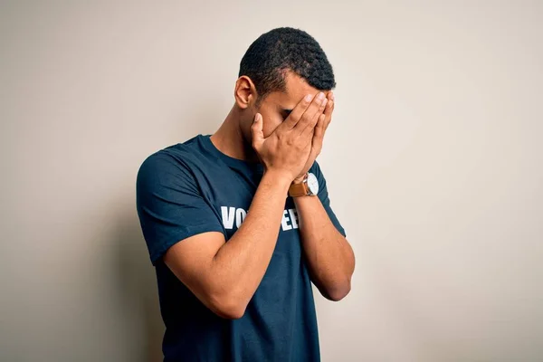泣きながら手で顔を覆う悲しい表情でボランティアメッセージが書かれたTシャツを着た若いハンサムなアフリカ系アメリカ人男性ボランティア うつ病の概念 — ストック写真