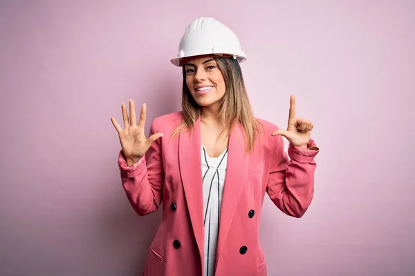 Молодая Красивая Брюнетка Архитектор Женщина Защитном Шлеме Розовом Фоне Показывая — стоковое фото
