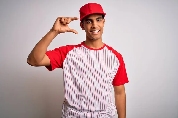 年轻英俊的非洲裔美国运动员 身穿条纹棒球T恤 头戴帽子 微笑着 手拿着小尺寸标志 手拿着手指 手拿着相机 自信地做手势 计量概念 — 图库照片