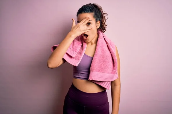 年轻美丽的女运动员 用毛巾遮住粉红的背景 用手捂住脸和眼睛 尴尬地看着手指 做运动 — 图库照片