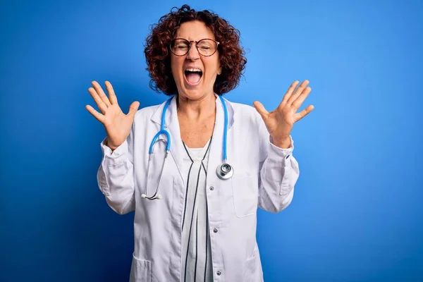 Lockige Ärztin Mittleren Alters Mantel Und Stethoskop Vor Blauem Hintergrund — Stockfoto