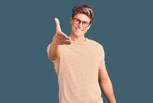 年轻英俊的男人穿着休闲装 戴着眼镜 友善地微笑 握手致意和欢迎 成功的商业 — 图库照片