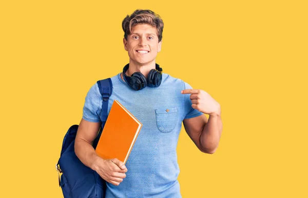 Joven Hombre Guapo Usando Mochila Estudiante Auriculares Sosteniendo Libro Señalando — Foto de Stock