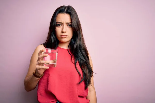 若いですブルネット女性飲むAガラスの新鮮な水以上ピンク隔離された背景とともに自信を持って式上のスマート顔考え深刻な — ストック写真
