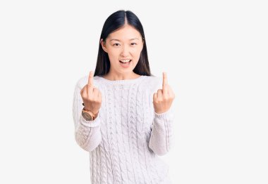 Young beautiful chinese woman wearing casual sweater showing middle finger doing fuck you bad expression, provocation and rude attitude. screaming excited 