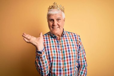 Sarı arka planda kralın altın tacını takmış yaşlı yakışıklı adam gülümsüyor ve avucunun içi kameraya bakıyor..