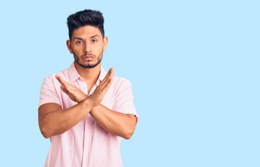 Yakışıklı Latin Amerikalı genç adam günlük tişört giyiyor. Reddedilmiş yüz ifadesi. Kollar ve avuç içleri ters dönmüş, kızgın yüz ifadesi takınmış. 