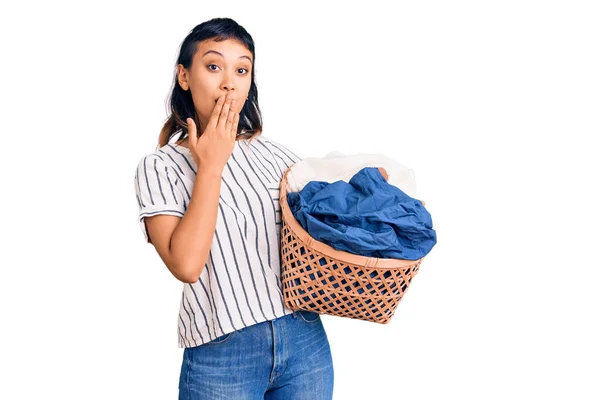 若い女性の手で口をカバー洗濯バスケットを保持し ショックを受け ミスを恐れている 驚きの表情 — ストック写真